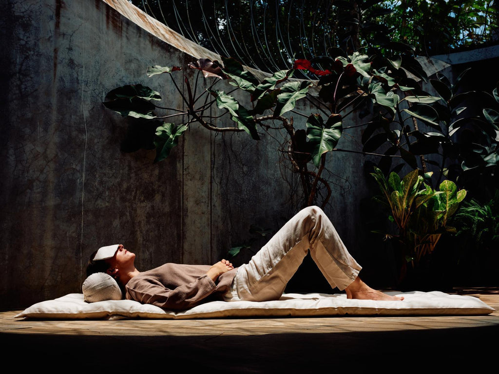 Person lying on a mat with plants in the background